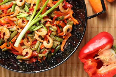 Photo of Shrimp stir fry with vegetables in wok and ingredients on table, flat lay