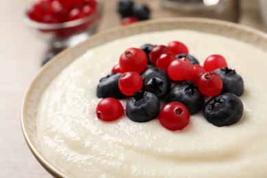 Photo of Delicious semolina pudding with berries in bowl on table, closeup