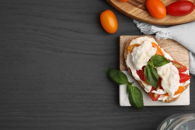 Photo of Delicious sandwich with burrata cheese and tomatoes served on grey wooden table, flat lay. Space for text