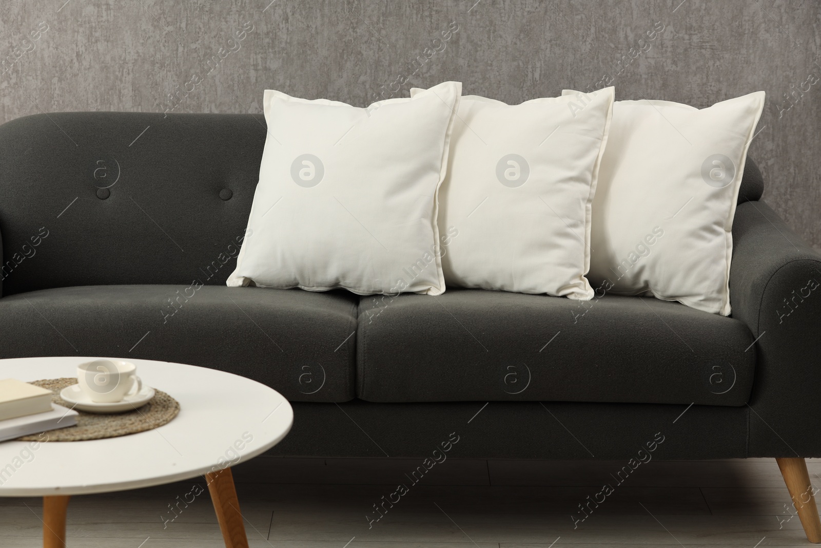 Photo of Soft white pillows on sofa and coffee table indoors