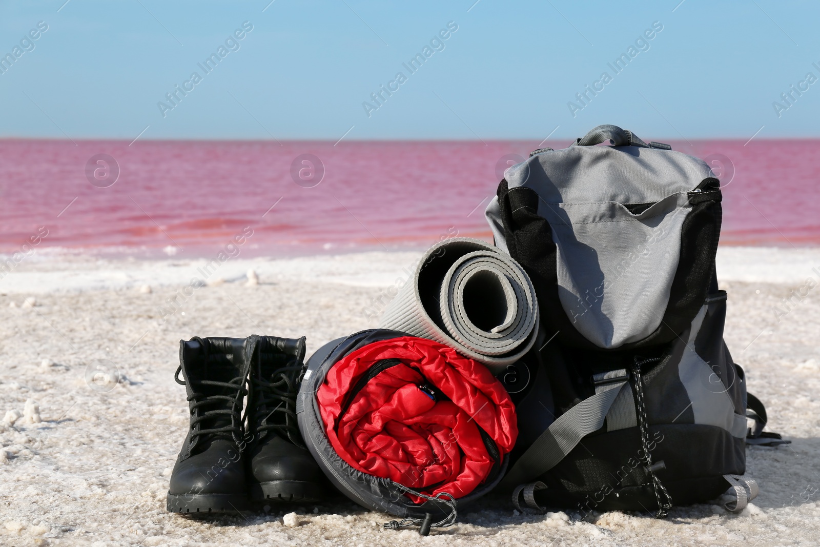 Photo of Set of camping equipment with sleeping bag on coast of pink lake