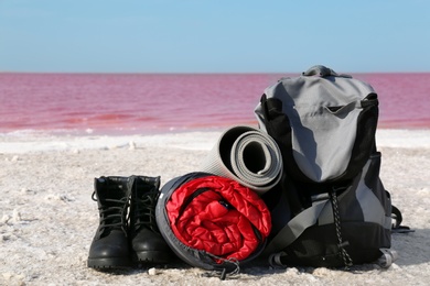 Set of camping equipment with sleeping bag on coast of pink lake