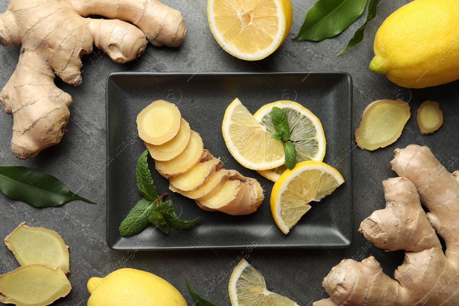 Photo of Fresh lemons, ginger and mint on grey table, flat lay