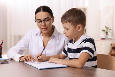 Photo of Dyslexia treatment. Teacher working with boy at table in room