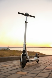Photo of Modern electric kick scooter outdoors at sunset