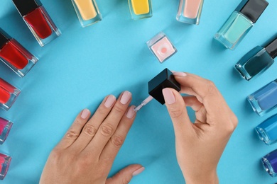 Photo of Woman applying nail polish on color background, above view