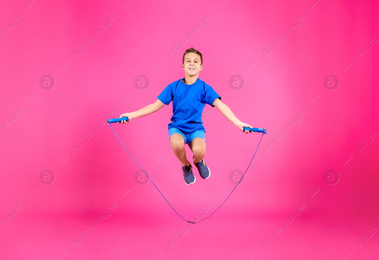 Photo of Full length portrait of boy jumping rope on color background