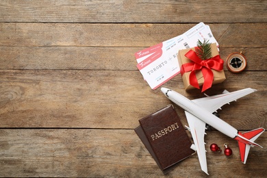 Photo of Flat lay composition with airline tickets, toy plane and passports on wooden table, space for text. Christmas vacation