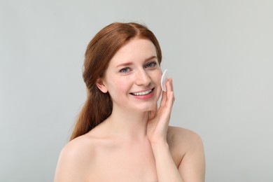 Photo of Smiling woman with freckles wiping face on grey background