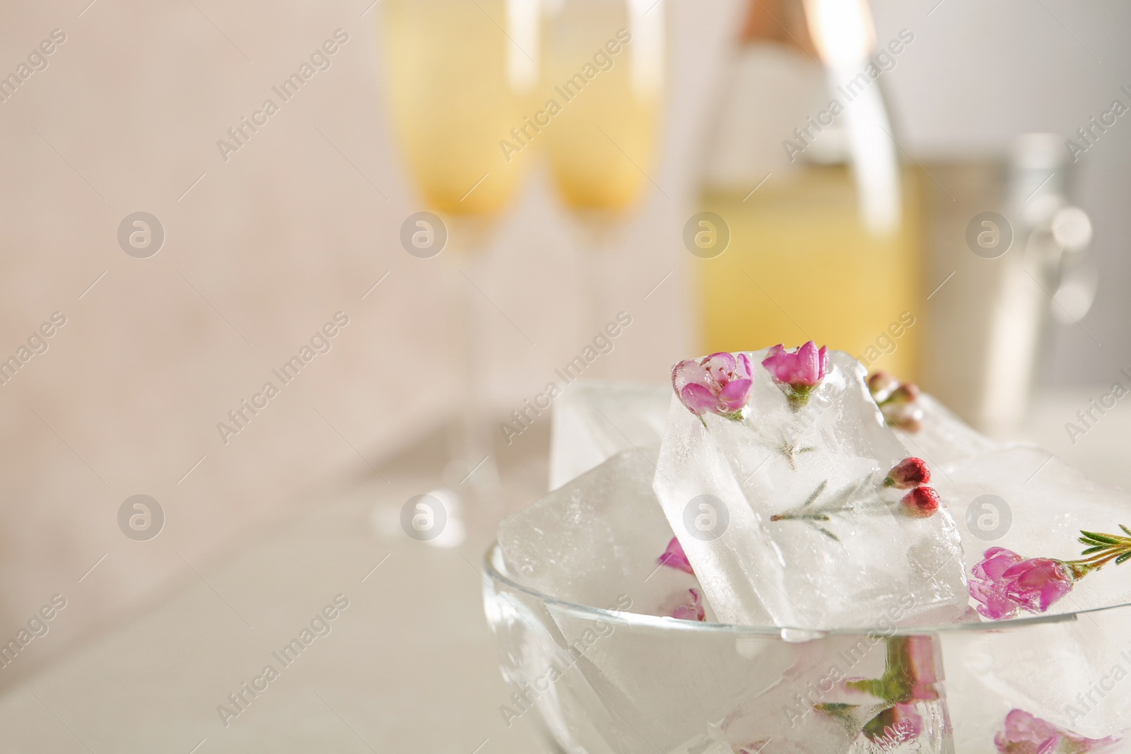 Photo of Bowl with floral ice cubes on table, closeup. Space for text