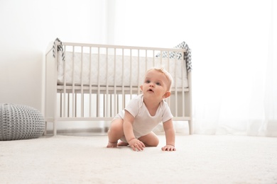 Cute little baby crawling on carpet indoors