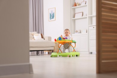 Photo of Cute little boy in baby walker at home