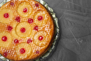 Photo of Plate with tasty pineapple cake on grey textured table, top view. Space for text