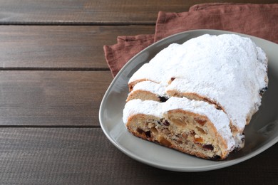 Photo of Traditional Christmas Stollen with icing sugar on wooden table, space for text