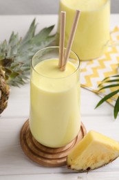 Tasty pineapple smoothie on white wooden table