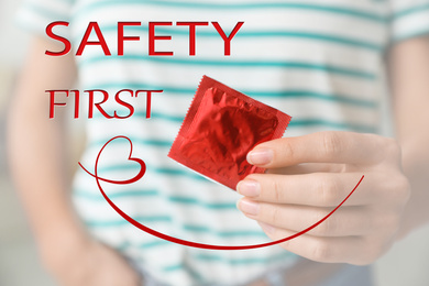 Image of Safety first. Woman holding condom indoors, closeup