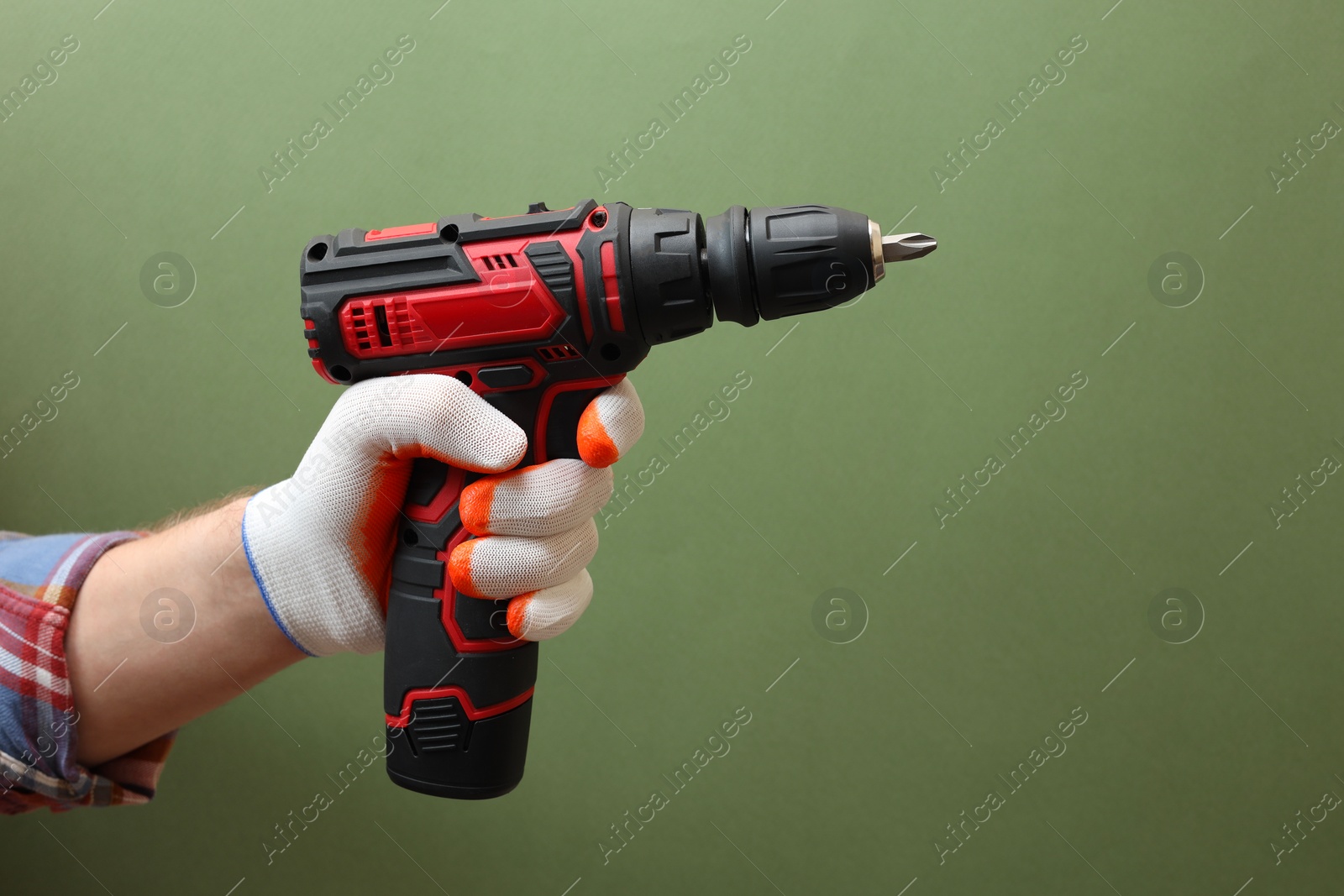 Photo of Handyman holding electric screwdriver on pale green background, closeup. Space for text