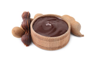 Photo of Bowl of tamarind sauce and fresh pods isolated on white