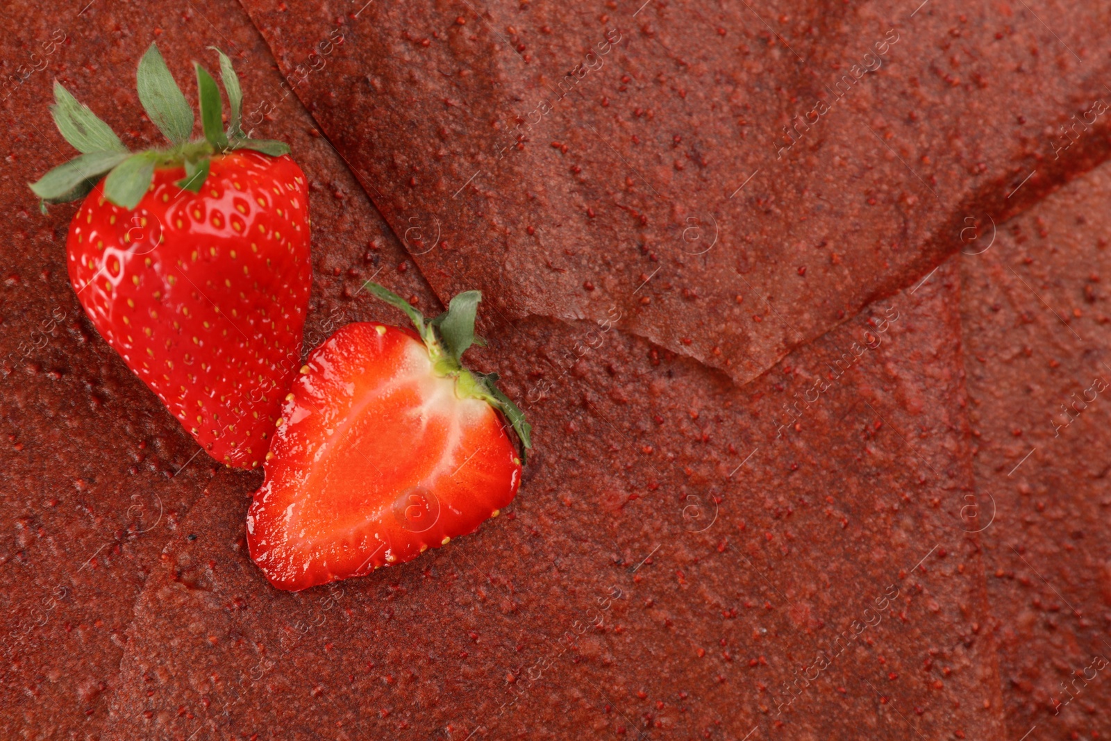 Photo of Strawberries on delicious fruit leather, flat lay. Space for text