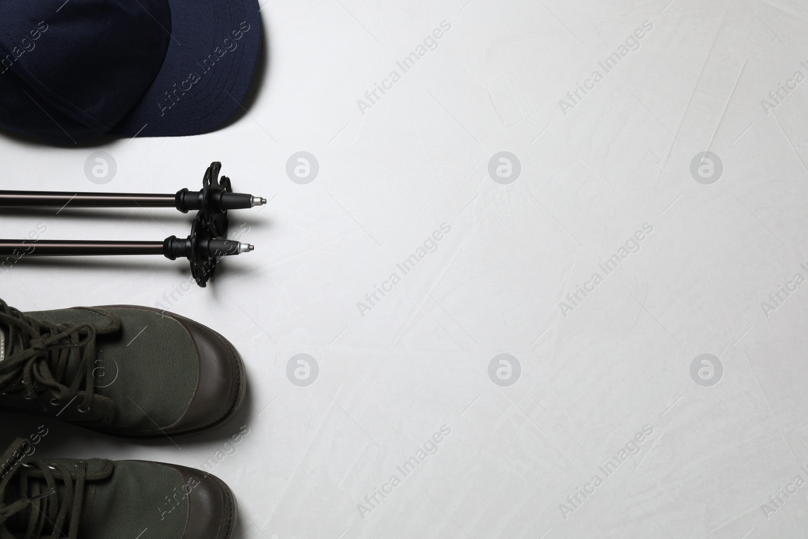 Photo of Flat lay composition with trekking poles and other hiking equipment on light background, space for text