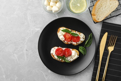 Photo of Tasty fresh tomato bruschettas on grey marble table, flat lay