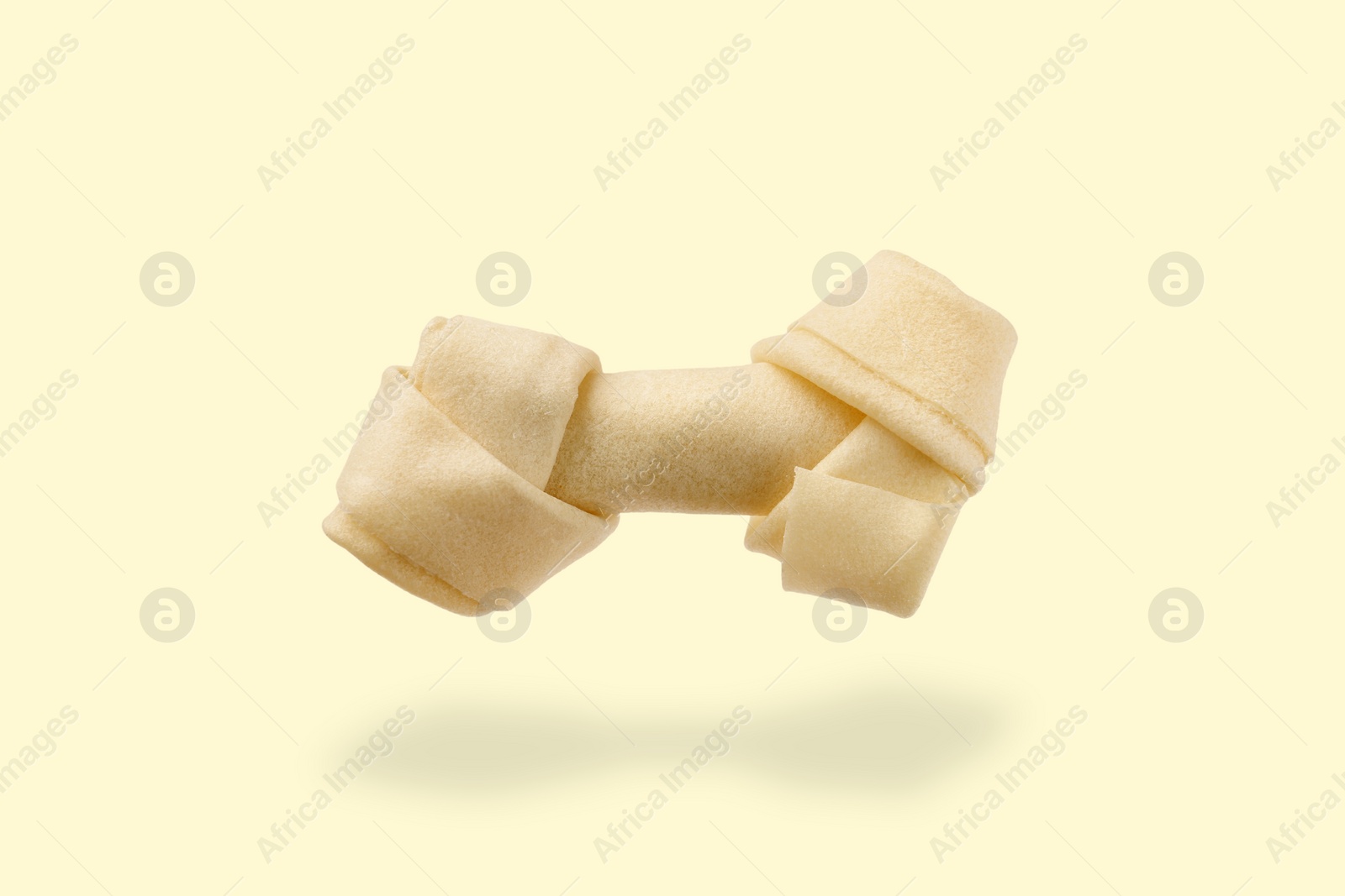 Image of Bone dog treat in air on beige background