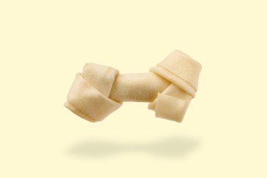 Image of Bone dog treat in air on beige background