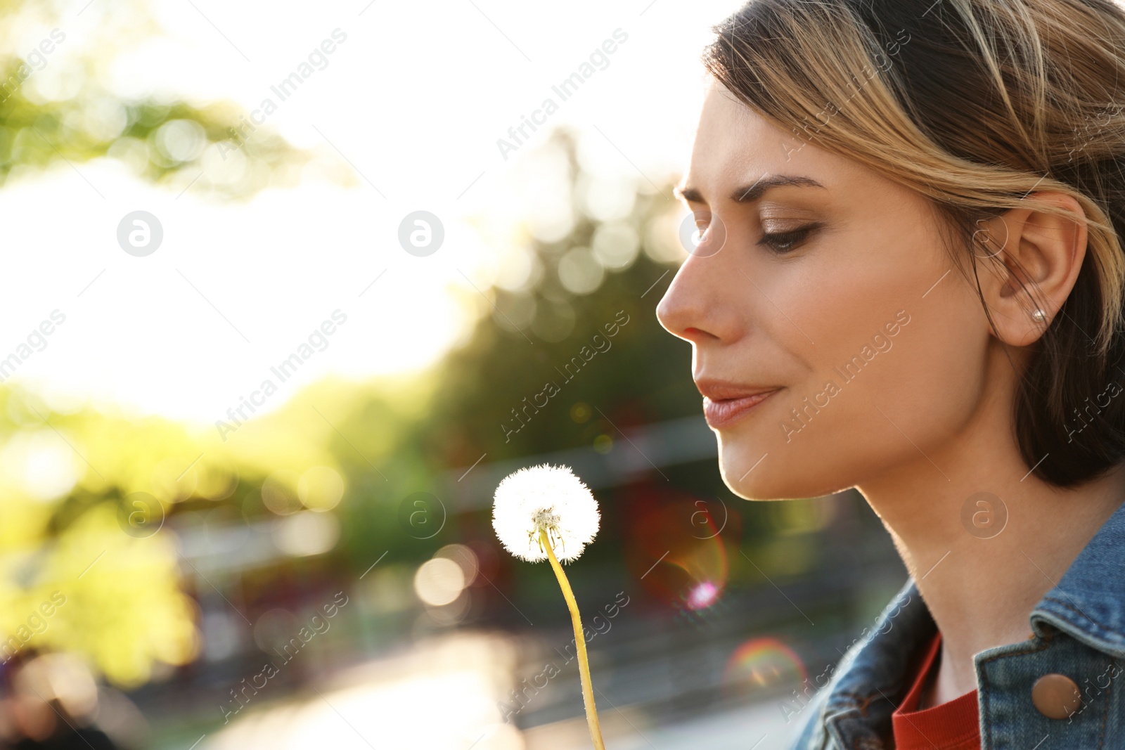 Photo of Young woman with dandelion in park on sunny day. Allergy free concept