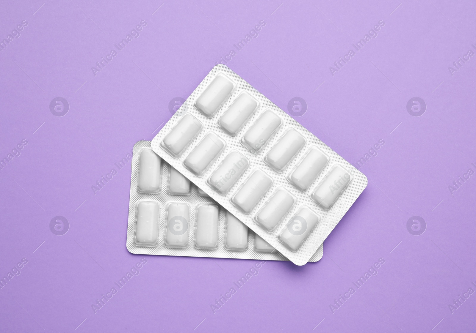 Photo of Blisters with chewing gums on violet background, flat lay