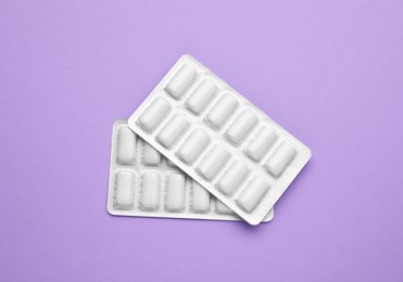 Photo of Blisters with chewing gums on violet background, flat lay