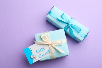 Photo of Gift card and presents on violet background, flat lay