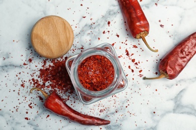 Photo of Jar with crushed chili pepper and pods on light background