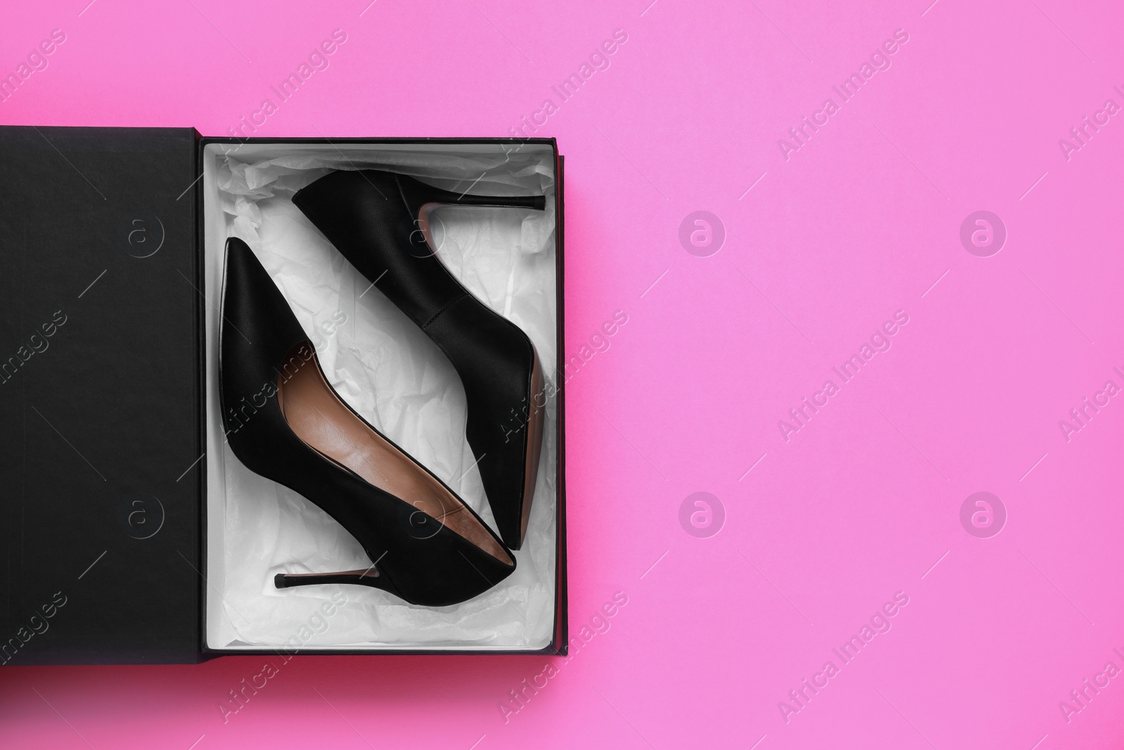 Photo of Stylish women's shoes in cardboard box on pink background, top view. Space for text