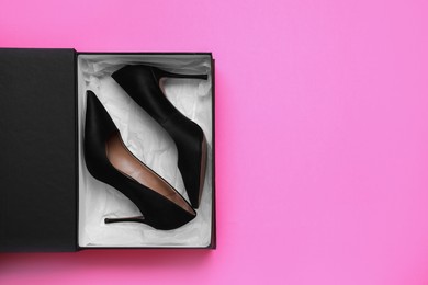 Photo of Stylish women's shoes in cardboard box on pink background, top view. Space for text