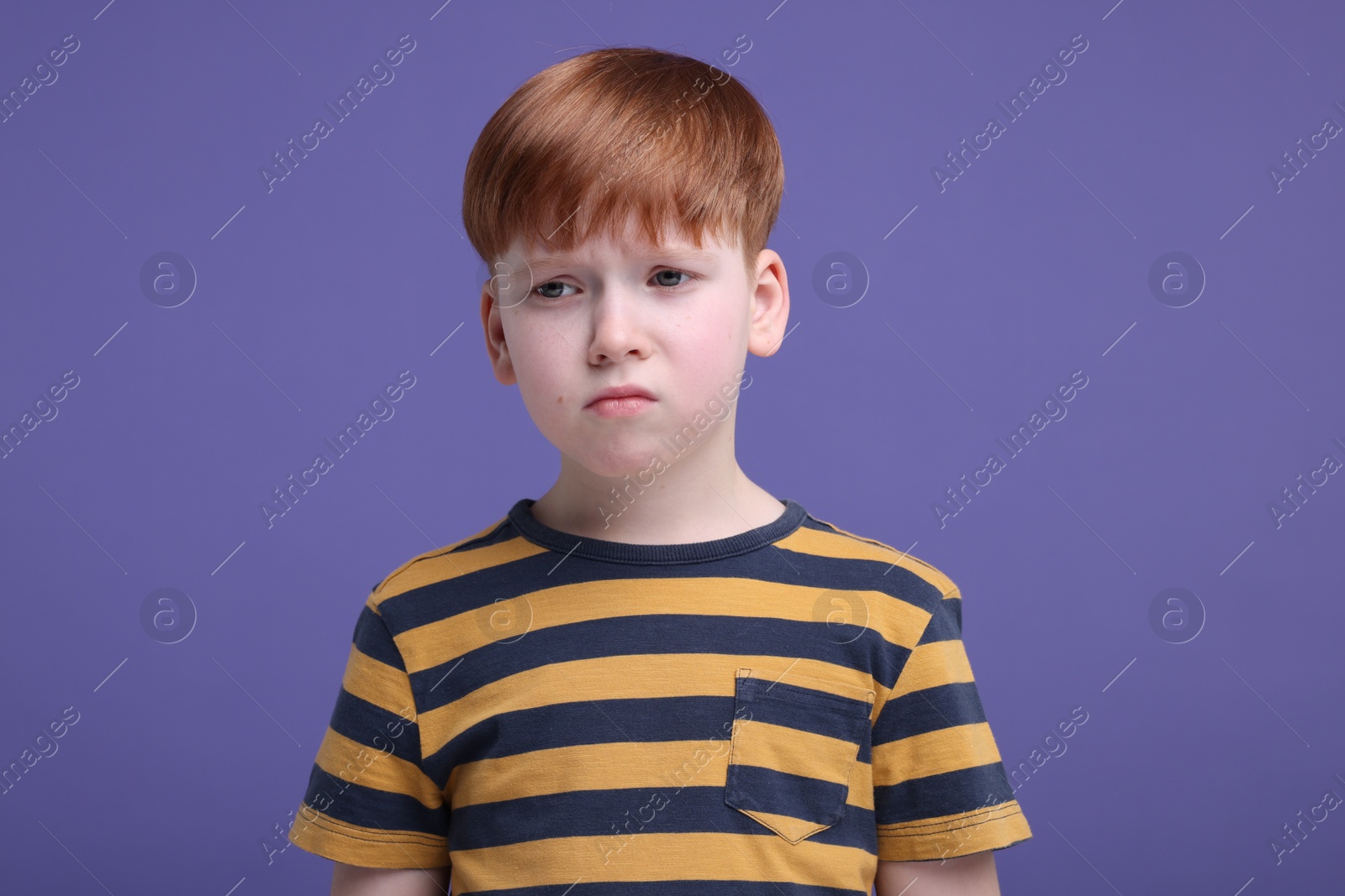 Photo of Portrait of sad little boy on purple background