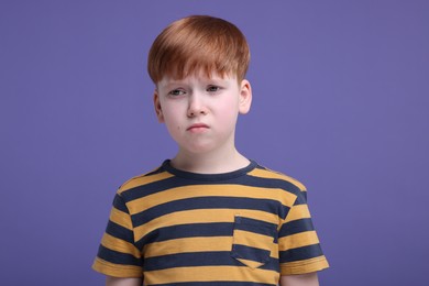 Portrait of sad little boy on purple background