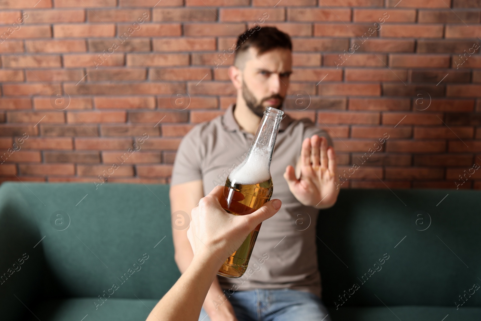 Photo of Man refusing to drink beer indoors, closeup. Alcohol addiction treatment