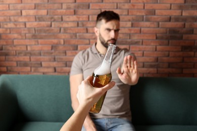 Man refusing to drink beer indoors, closeup. Alcohol addiction treatment