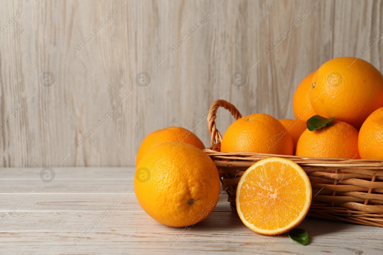 Photo of Many whole and cut oranges on light wooden table, space for text