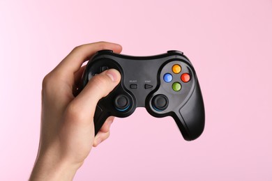 Photo of Man using wireless game controller on pink background, closeup