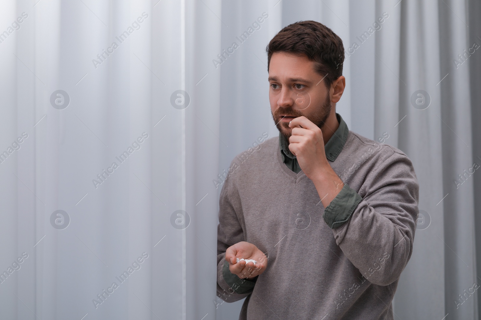 Photo of Depressed man taking antidepressant pill indoors, space for text