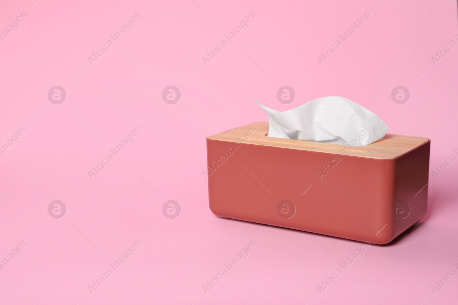 Photo of Holder with paper tissues on pink background. Space for text