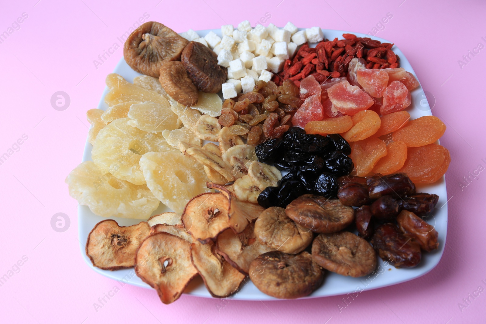 Photo of Plate with different dried fruits on violet background