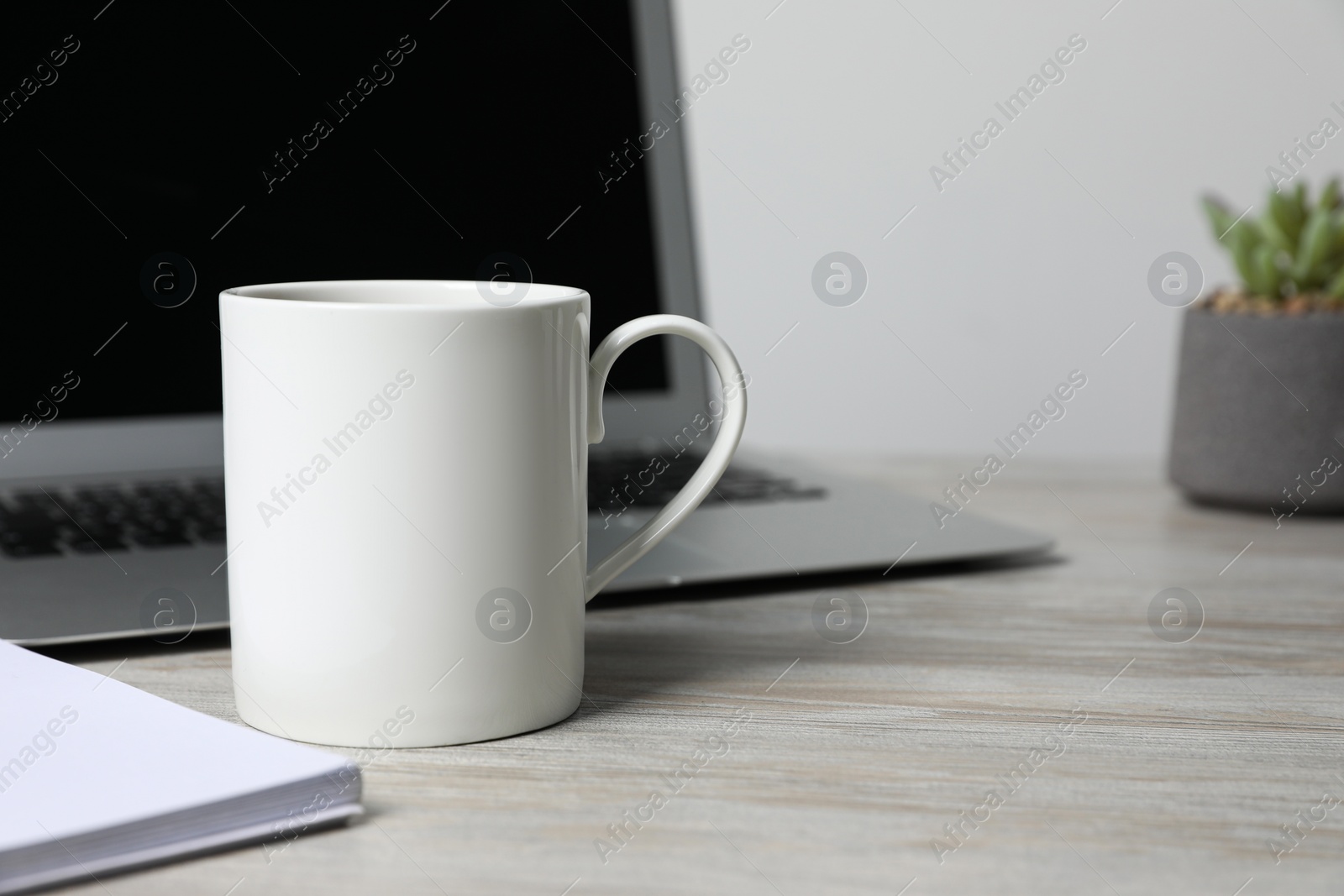 Ceramic mug, laptop and notebook on white wooden table, closeup. Space for text Photo of Ceramic mug, laptop and notebook on white wooden table, closeup. Space for text
