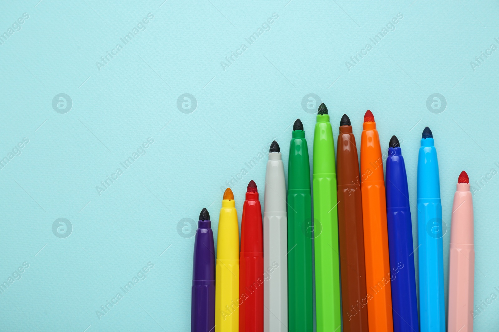 Photo of Different colorful markers on light blue background, flat lay. Space for text