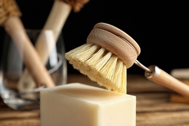 Cleaning brush and soap bar for dish washing on wooden table, closeup
