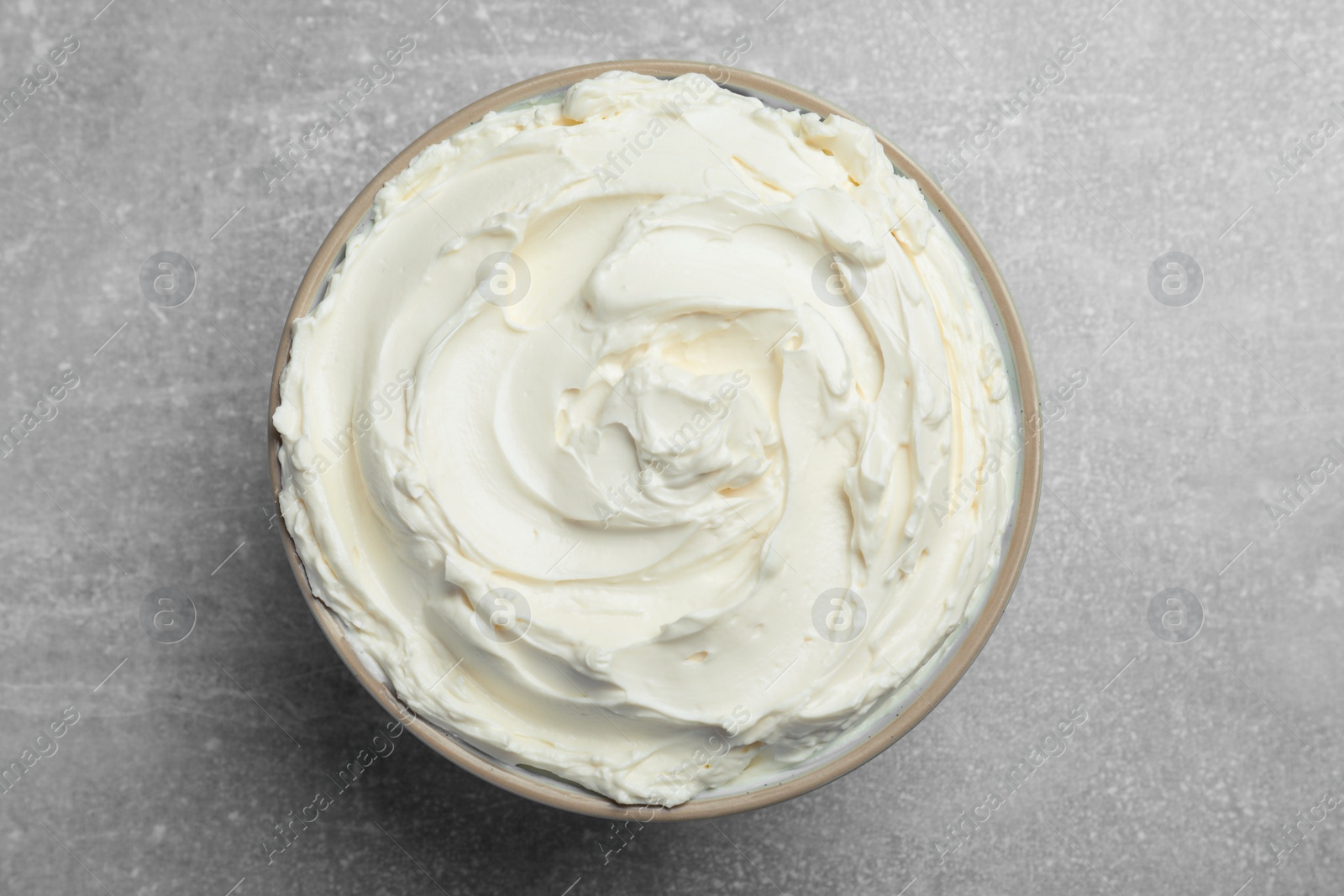 Photo of Bowl of tasty cream cheese on light grey table, top view