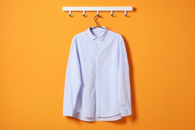 Photo of Hanger with striped shirt on orange wall