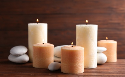 Composition of burning candles and spa stones on table