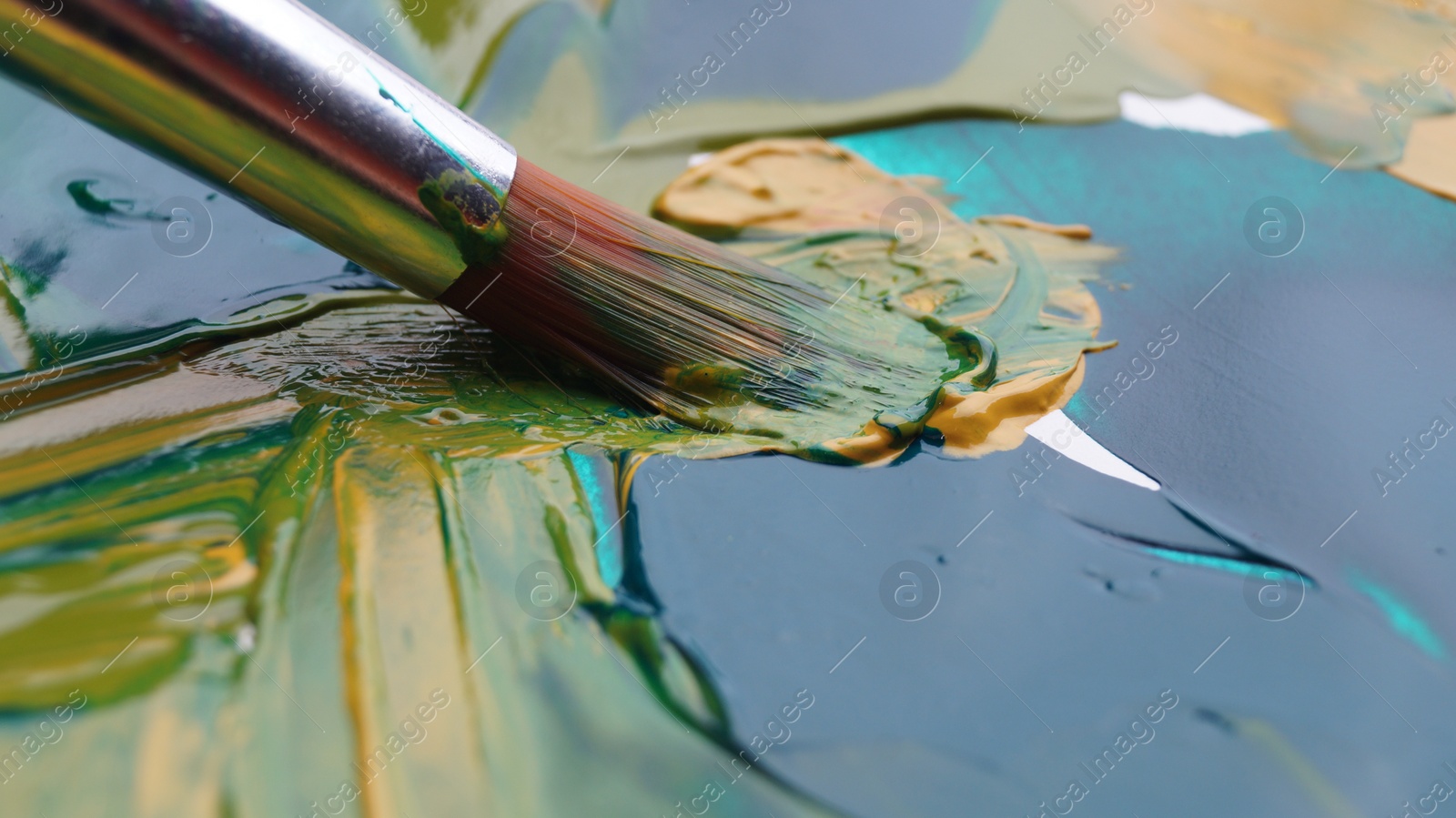 Photo of Brush on artist's palette with mixed paints, closeup